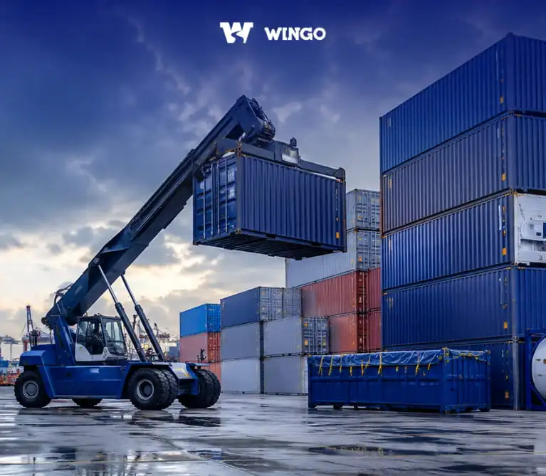 Container terminal with a reach stacker loading shipping containers for international freight transport.